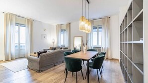 A modern living room with a sofa, a dining table with chairs, and a large bookshelf. - Apartment in Milan with 3 bedrooms sleeps 8 (Milan)