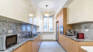 A narrow kitchen with granite countertops, stainless steel appliances, and wooden cabinets. - Apartment in Milan with 3 bedrooms sleeps 8 (Milan)