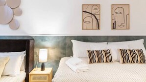 A neatly made bed with patterned pillows, a bedside lamp, and abstract wall art. - Apartment in Milan with 3 bedrooms sleeps 8 (Milan)
