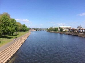 Un río con una senda peatonal a un lado y edificios al otro.