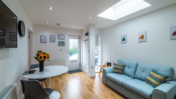 A modern living room with a sofa, a dining table with chairs, and a skylight. - Modern, Stylish 1 Bedroomed Apartment (Nottingham)