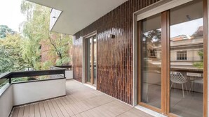 A balcony with a wooden floor, a glass door, and a view of trees and buildings. - Apartment in Milan with 4 bedrooms sleeps 7 (Milan)