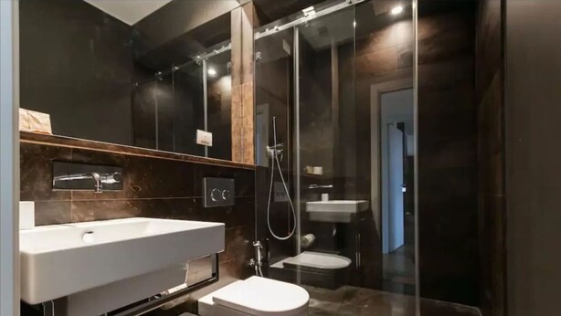 Een moderne badkamer met een douchecabine van glas, een wit wastafelmeubel en een toilet.