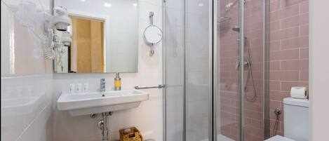 Un baño moderno con ducha envuelta en vidrio, lavamanos con espejo e inodoro.