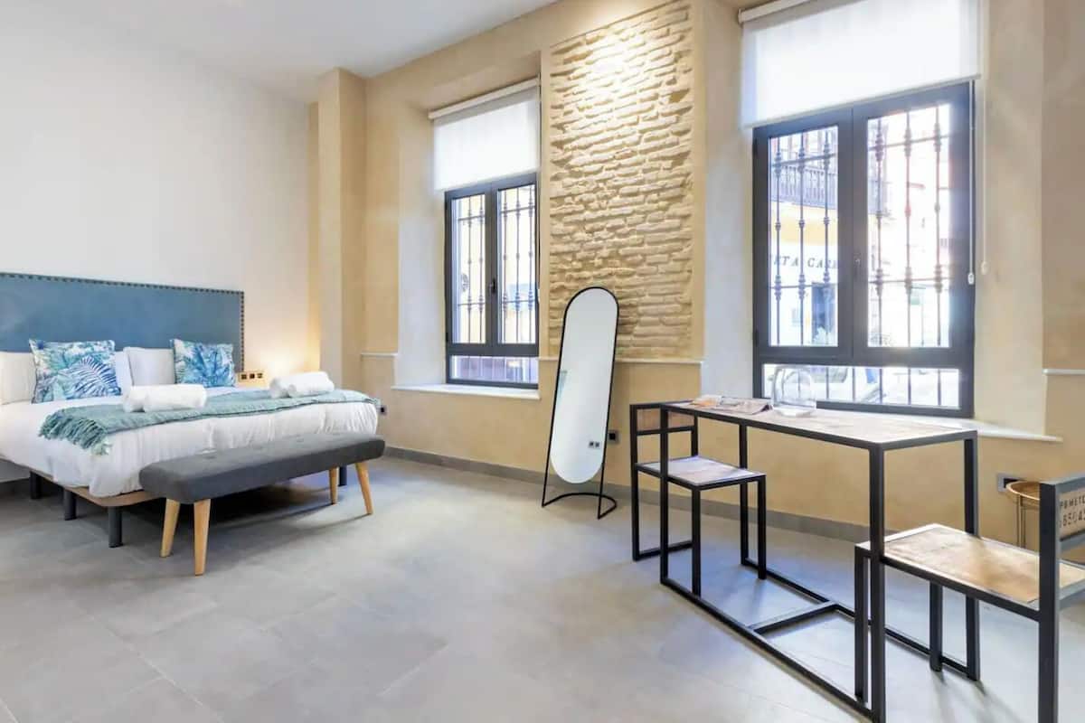 A modern bedroom with a bed, a desk, and a stone accent wall.