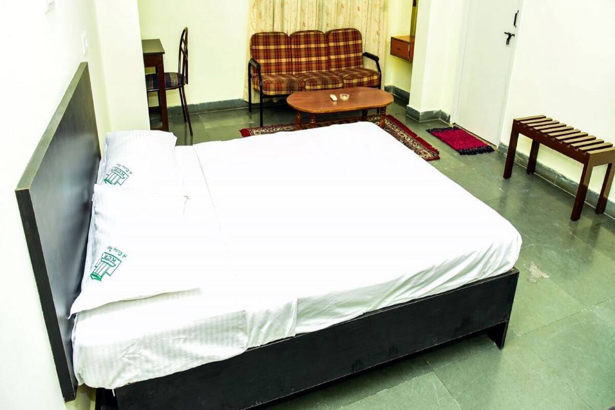 A room with a bed, a chair, a small table, and a bench.