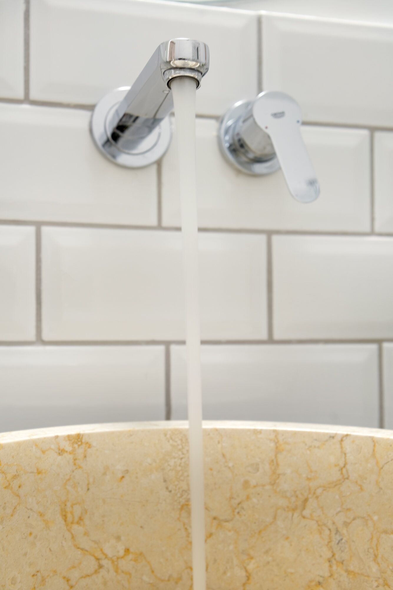 A bathroom with a marble sink and chrome faucets.