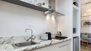 Ett modernt kök med en bänkskiva i marmor, en diskho i rostfritt stål och en inbyggd köksfläkt.