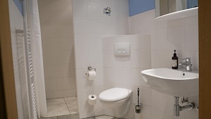 A bathroom with a toilet, sink, and shower. - Ferienwohnung Leuchtturm (Fehmarn)