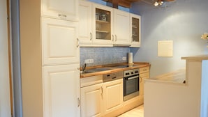A kitchen with white cabinets, a blue tiled backsplash, and a wooden countertop. - Ferienwohnung Leuchtturm (Fehmarn)