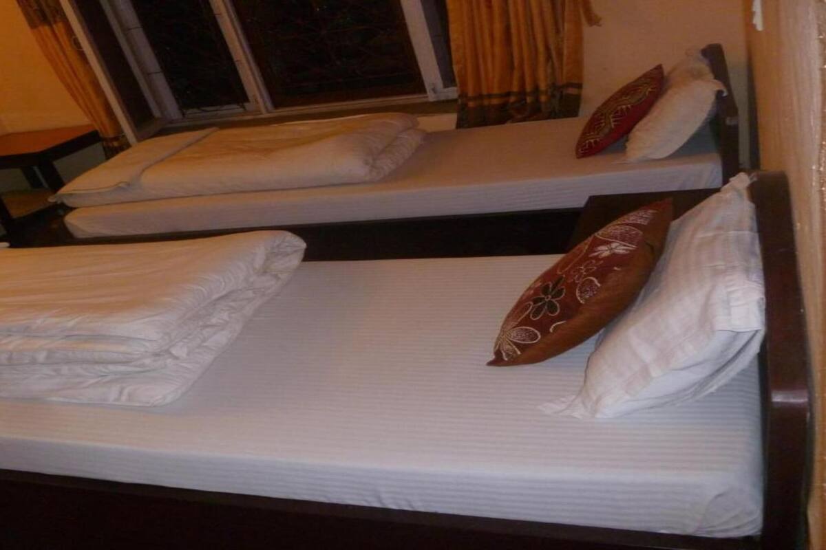 Ein Zimmer mit zwei Einzelbetten, jeweils mit Kissen und Decke.