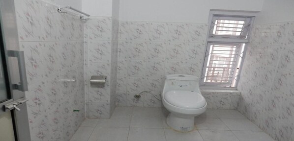 Un baño con inodoro, secamanos y ventana.