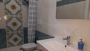 Une salle de bain équipée d’une douche, de toilettes, d’un bidet et d’un lavabo.