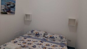 Une chambre à coucher avec un lit, un tableau représentant un bateau et un climatiseur fixé au mur.
