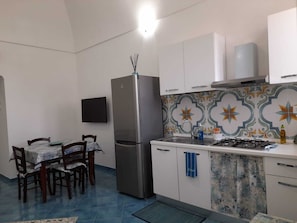 A compact kitchen with a refrigerator, a gas stove, and a tiled backsplash.