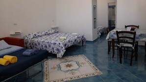 Une pièce avec deux lits, un canapé, une table à manger avec des chaises et un sol carrelé.