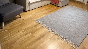 Un salon avec un canapé, une petite table, une lampe, un tapis et une fenêtre donnant sur un beau paysage.