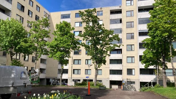 Un immeuble résidentiel à plusieurs étages avec un espace de stationnement à l’avant.