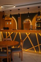 Een bar met houten meubels, hanglampen en een bargedeelte met flessen.