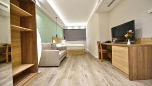 Una habitación pequeña con cama, sofá, escritorio y televisor.