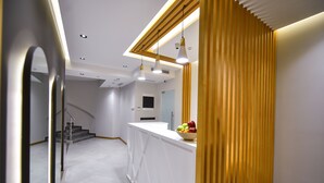Interior moderno de hotel con una recepción blanca, una escalera y un separador de madera.