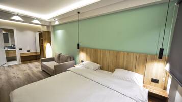 A modern hotel room with a large bed, a wooden headboard, a small seating area, and a mirror.