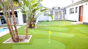 A miniature golf course with artificial grass, a pool, and a white building with a red door. - Elgibor Best Guest House  (Cape Town)