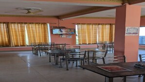 A restaurant with tables and chairs, a ceiling fan, and a television on the wall. - Great View Hotel And Restaurant (Tehri)