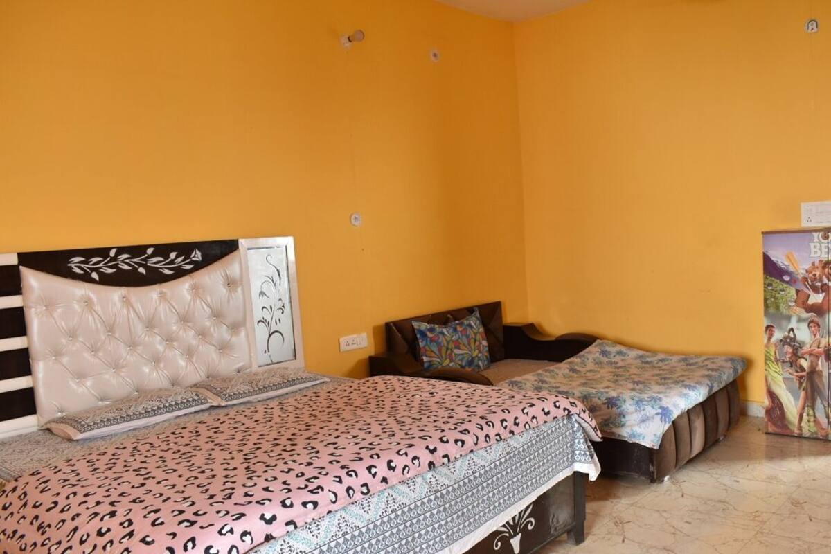 Una habitación con una cama grande, dos camas más pequeñas, un cabecero con un panel decorativo y una pared con un mural.