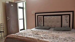 A bedroom with a bed, a chair, a door, and a window. - Great View Hotel And Restaurant (Tehri)