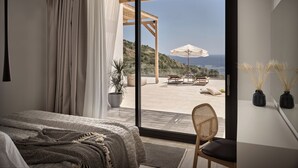 Een slaapkamer met een grote schuifpui die leidt naar een terras met tafel en stoelen, uitzicht op zee, en een pergola.