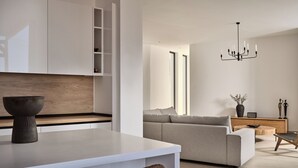 Een moderne woonkamer met een bank, een salontafel en een eethoek met een stoel en een vaas.