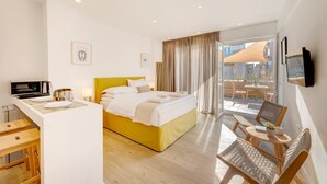 A modern hotel room with a bed, a desk, and a balcony with seating. - Executive Apartment With Private Terrace-d (Piraeus)