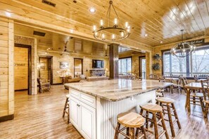 Relax in a spacious cabin-style building with a central island, comfortable seating areas, and a mounted TV for entertainment.