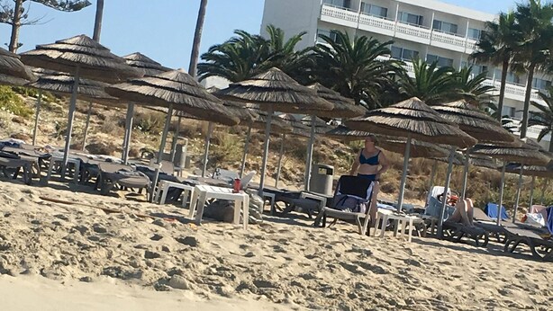 A beach with umbrellas, lounge chairs, and a building labeled "Nissi Beach" in the background. - Narcissos Nissi Beach Apartment C12 (Ayia Napa)
