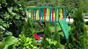 Un parque infantil con una estructura de juego colorida, rodeado de abundante vegetación.