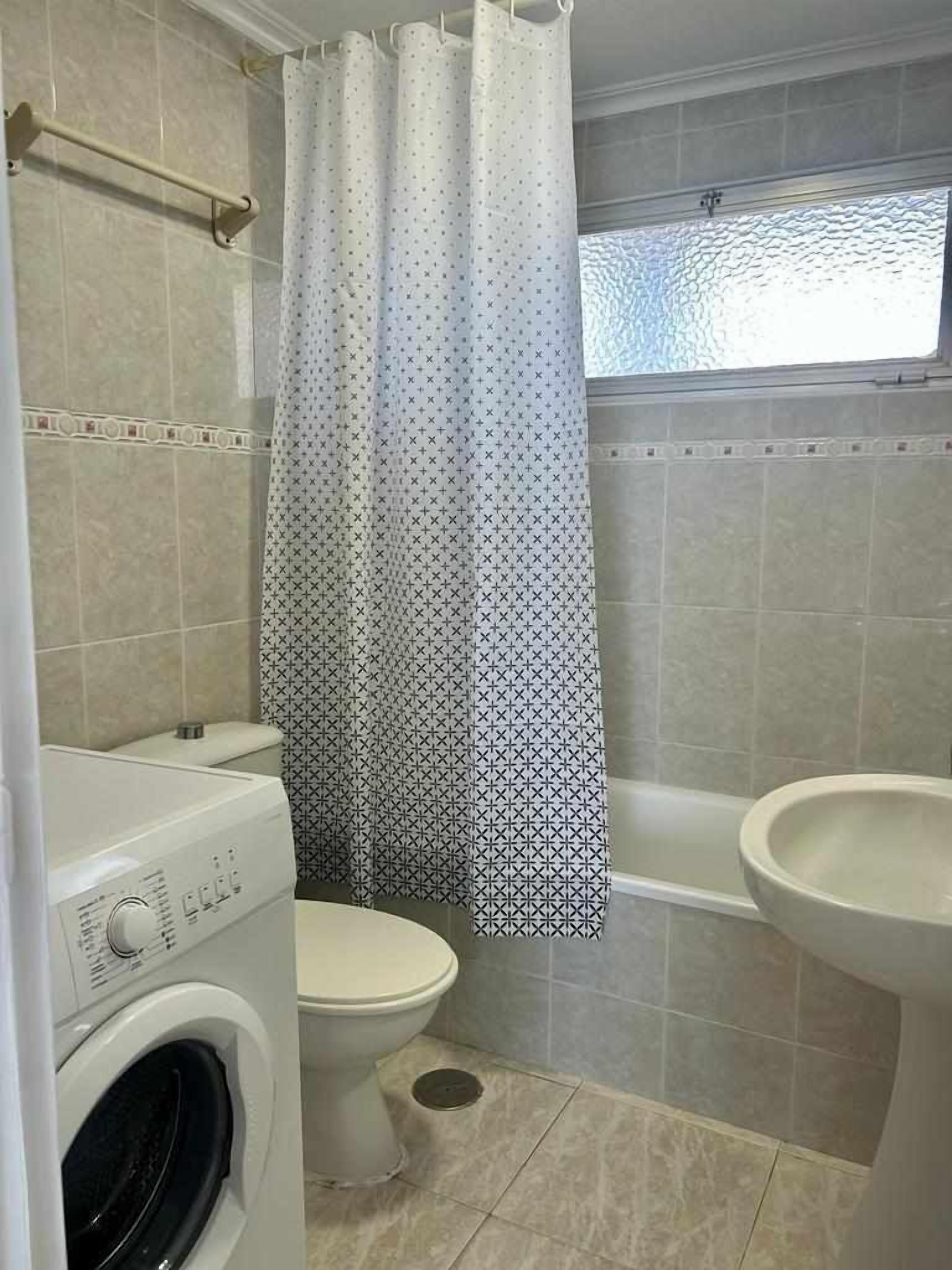 Une salle de bain équipée d’un lave-linge, de toilettes et d’une baignoire.