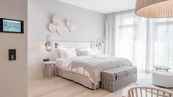 A modern bedroom with a bed, bedside tables, a wicker basket, and a small seating area.
