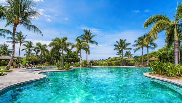 A clear blue pool surrounded by palm trees and lounge chairs. - 🏖️Kulalani Townhome w/ Mountain Views + Beach Club Access (Kamuela)