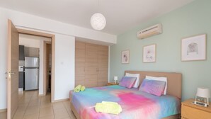 A bedroom with a bed, bedside tables, a wardrobe, and an air conditioning unit. - Narcissos Nissi Beach Apartment C3 (Ayia Napa)