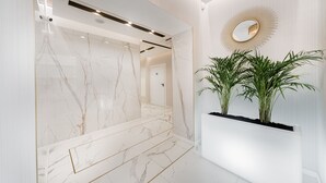 Un bagno moderno con un elegante mobile lavabo in marmo, uno specchio grande e una pianta in vaso.