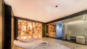 Un bagno moderno con pavimento in marmo, una panca bianca particolare e cabina doccia in vetro.