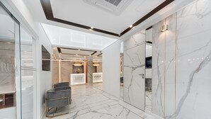 Una hall d'albergo moderna con pavimento in marmo, pareti in vetro e arredi contemporanei.