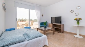 Una habitación de hotel moderna con cama, televisor, mesa de centro y balcón con vistas.