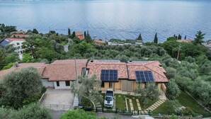 Ein Haus mit roten Ziegeln auf dem Dach, Solaranlage und einem geparkten Auto davor.