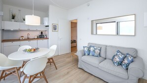 Ein moderner Wohnraum mit Küche, Essbereich und einer Couch mit floralen Kissen.