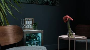 Un área de bar moderna con un enfriador de vino, un jarrón con flores rosas y un cuadro en la pared.