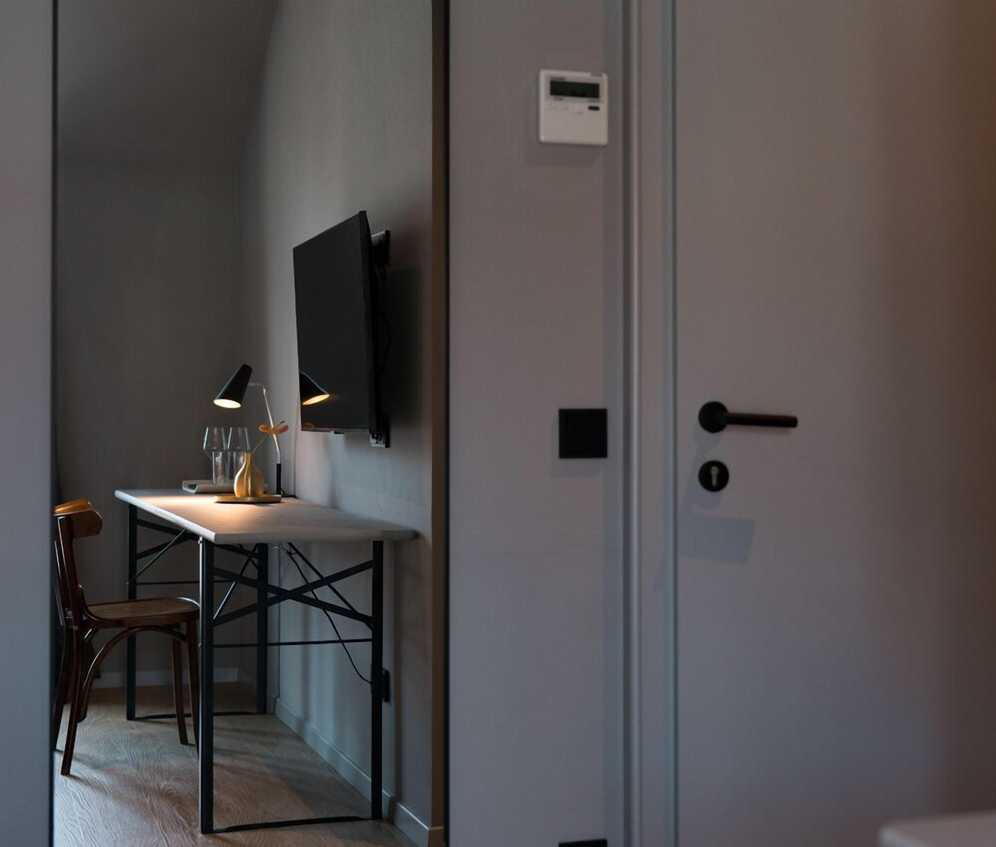 Een moderne kamer met een bureau, stoel en een wandgemonteerde televisie.