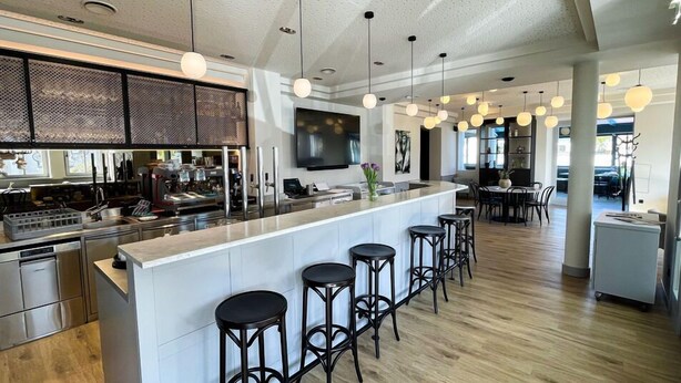 Una cocina moderna con una isla central, taburetes de bar e iluminación colgante.