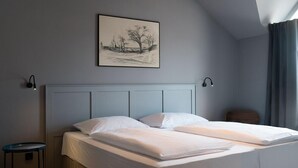 Un dormitorio moderno con una cama grande, una mesita de noche pequeña y un cuadro enmarcado en la pared.